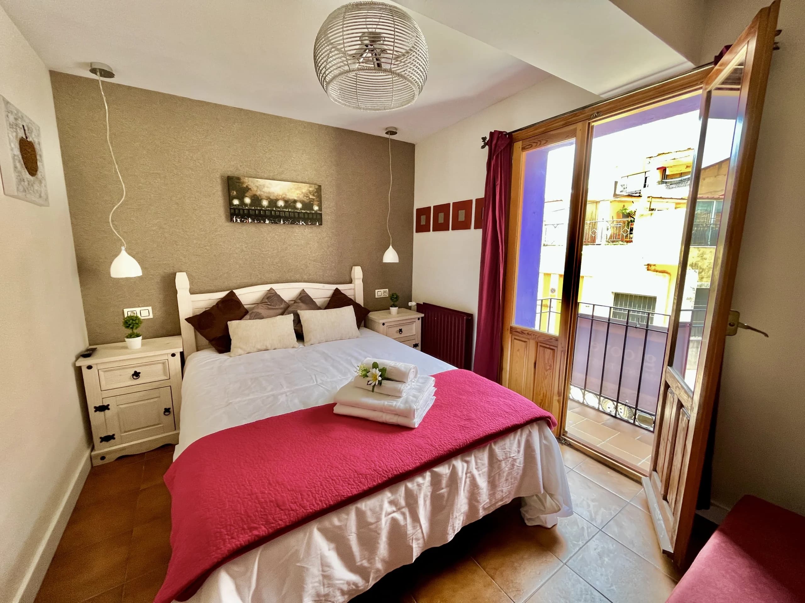 Habitación de matrimonio con cama doble vestida en blanco y cabecero de mimbre